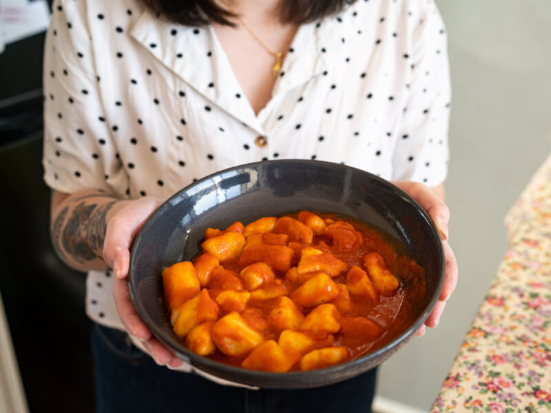 A woman holding a plate of DIY gnocchi